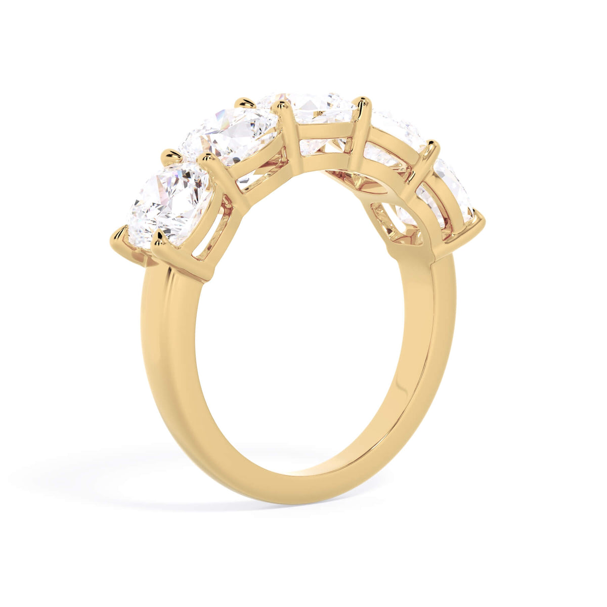 A picture of a five stone diamond wedding ring with cushion shape diamonds that are shared prong set in yellow gold on a white background with a slightly angled, through the finger view.