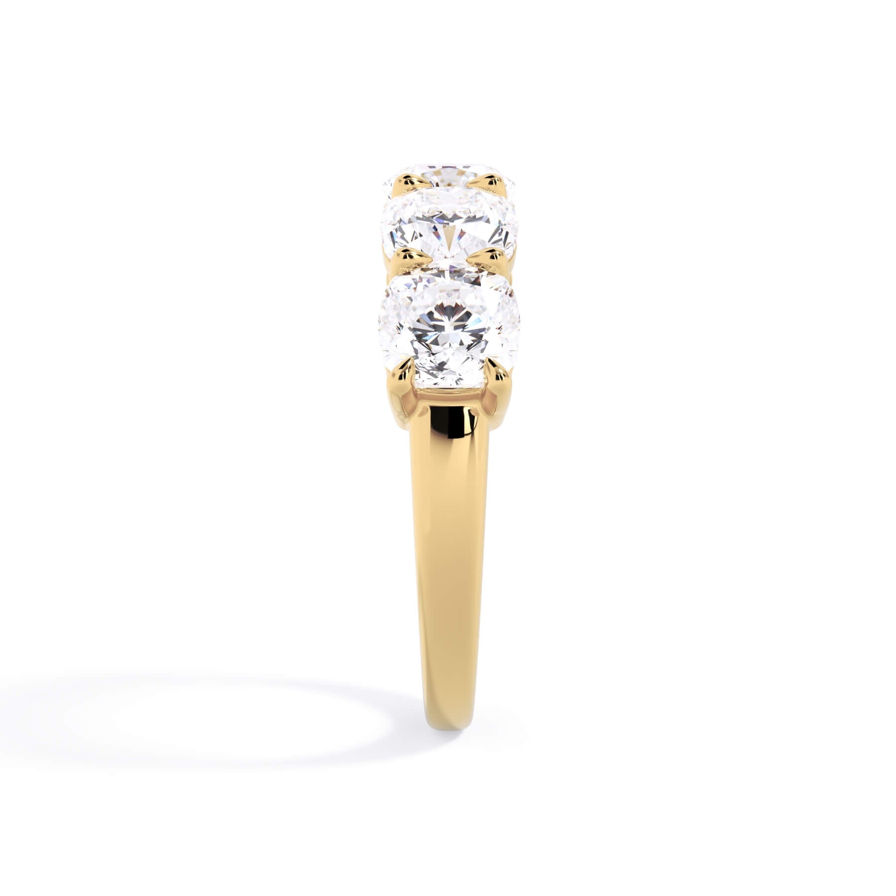 A picture of a five stone diamond wedding ring with cushion shape diamonds that are shared prong set in yellow gold on a white background with a side profile view.