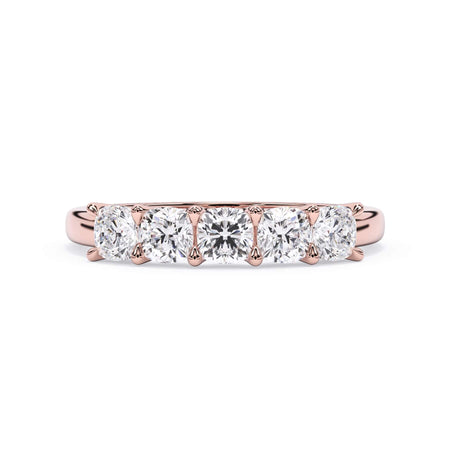 A picture of a five stone diamond wedding ring with cushion shape diamonds that are u prong set in rose gold on a white background with the ring facing forward, lying down.