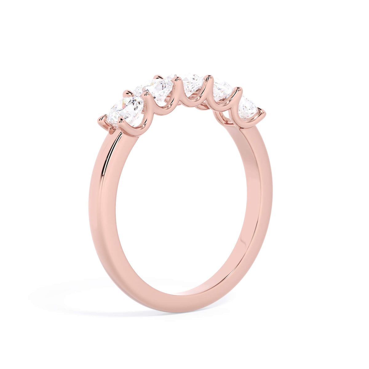 A picture of a five stone diamond wedding ring with cushion shape diamonds that are u prong set in rose gold on a white background with a slightly angled, through the finger view.
