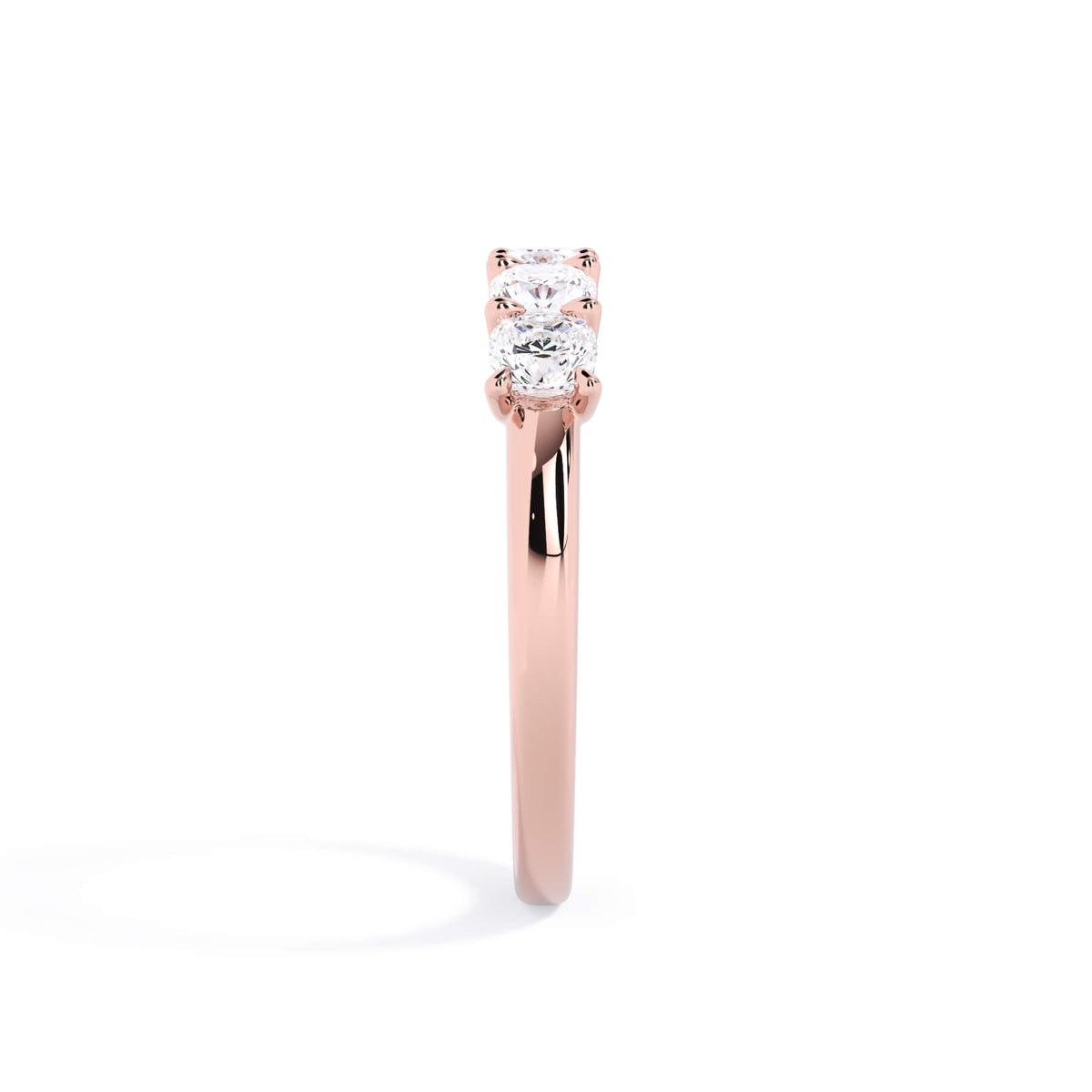 A picture of a five stone diamond wedding ring with cushion shape diamonds that are u prong set in rose gold on a white background with a side profile view.