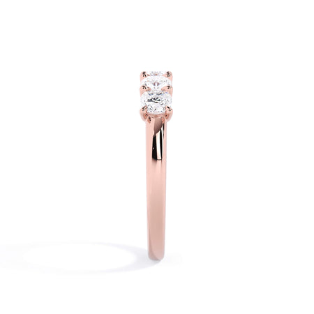 A picture of a five stone diamond wedding ring with cushion shape diamonds that are u prong set in rose gold on a white background with a side profile view.