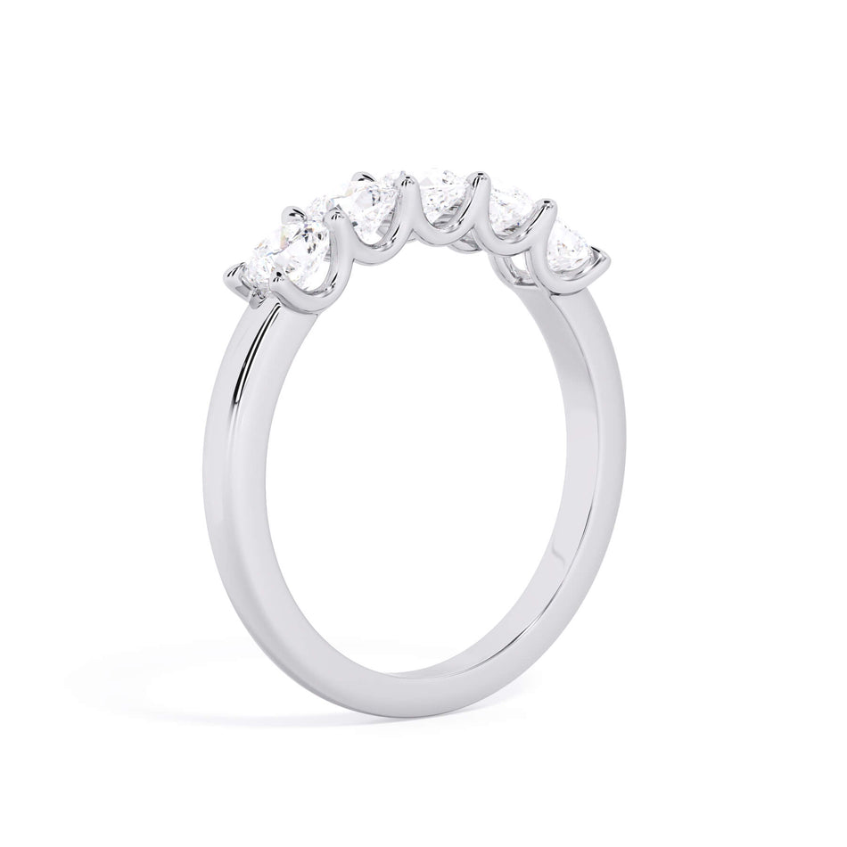 A picture of a five stone diamond wedding ring with cushion shape diamonds that are u prong set in white gold or platinum on a white background with a slightly angled, through the finger view.