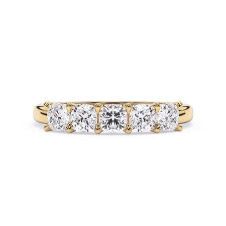 A picture of a five stone diamond wedding ring with cushion shape diamonds that are u prong set in yellow gold on a white background with the ring facing forward, lying down.
