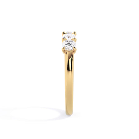 A picture of a five stone diamond wedding ring with cushion shape diamonds that are u prong set in yellow gold on a white background with a side profile view.