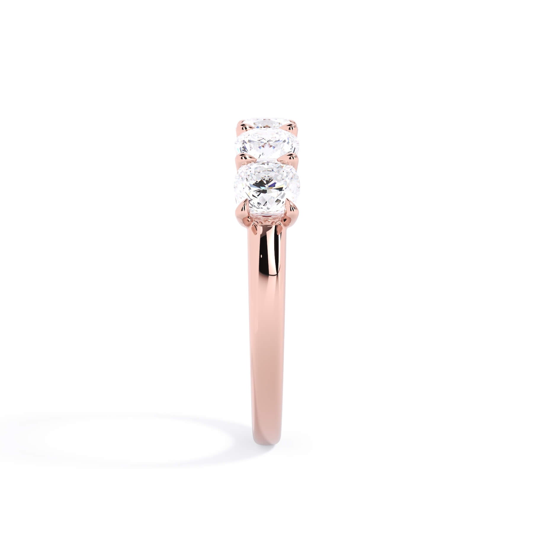 A picture of a five stone diamond wedding ring with cushion shape diamonds that are u prong set in rose gold on a white background with a side profile view.