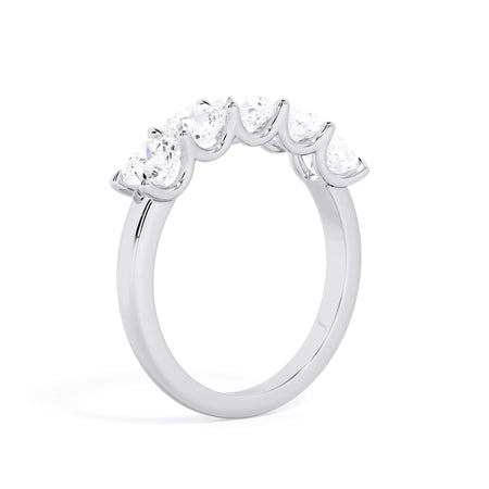 A picture of a five stone diamond wedding ring with cushion shape diamonds that are u prong set in white gold or platinum on a white background with a slightly angled, through the finger view.