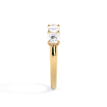 A picture of a five stone diamond wedding ring with cushion shape diamonds that are u prong set in yellow gold on a white background with a side profile view.