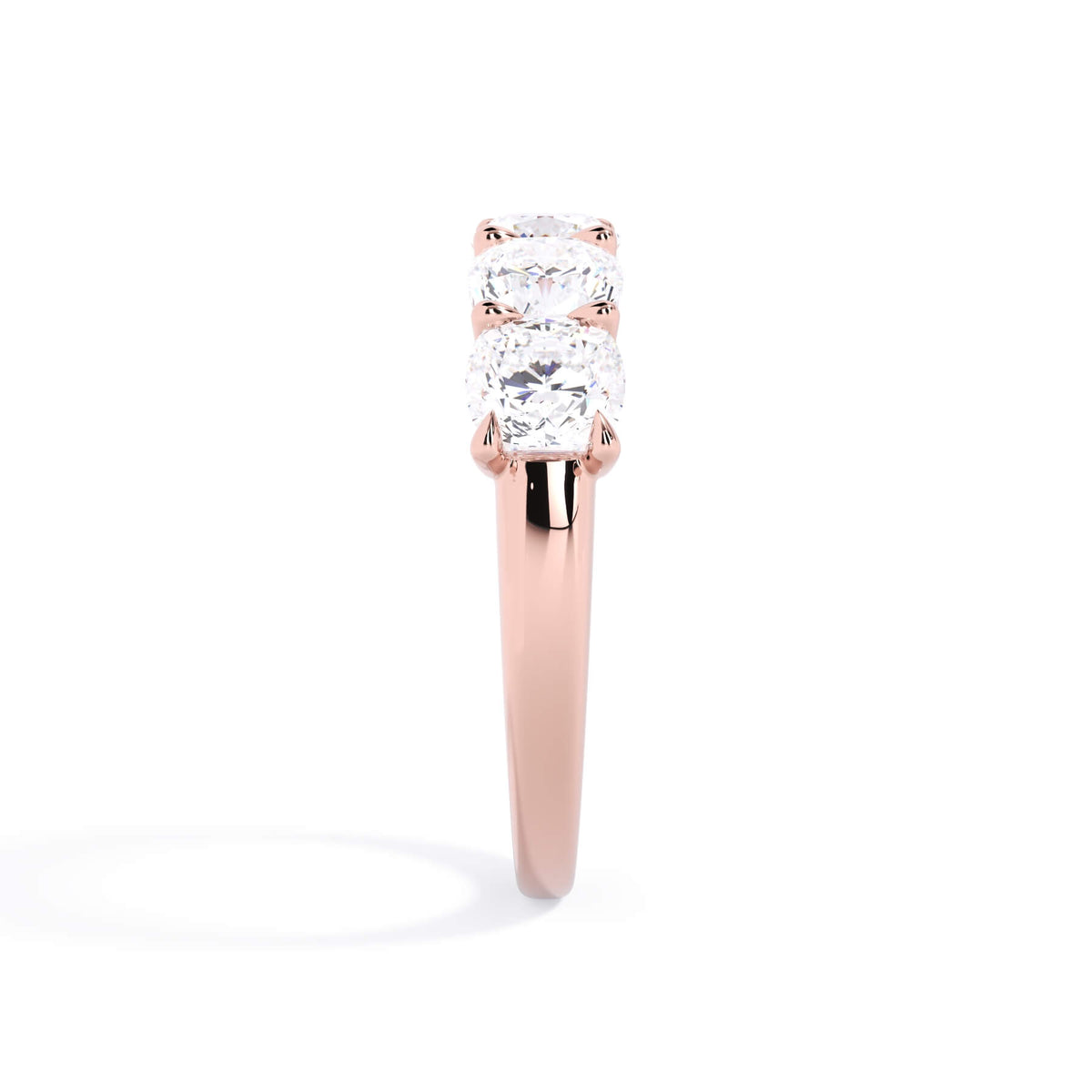 A picture of a five stone diamond wedding ring with cushion shape diamonds that are u prong set in rose gold on a white background with a side profile view.