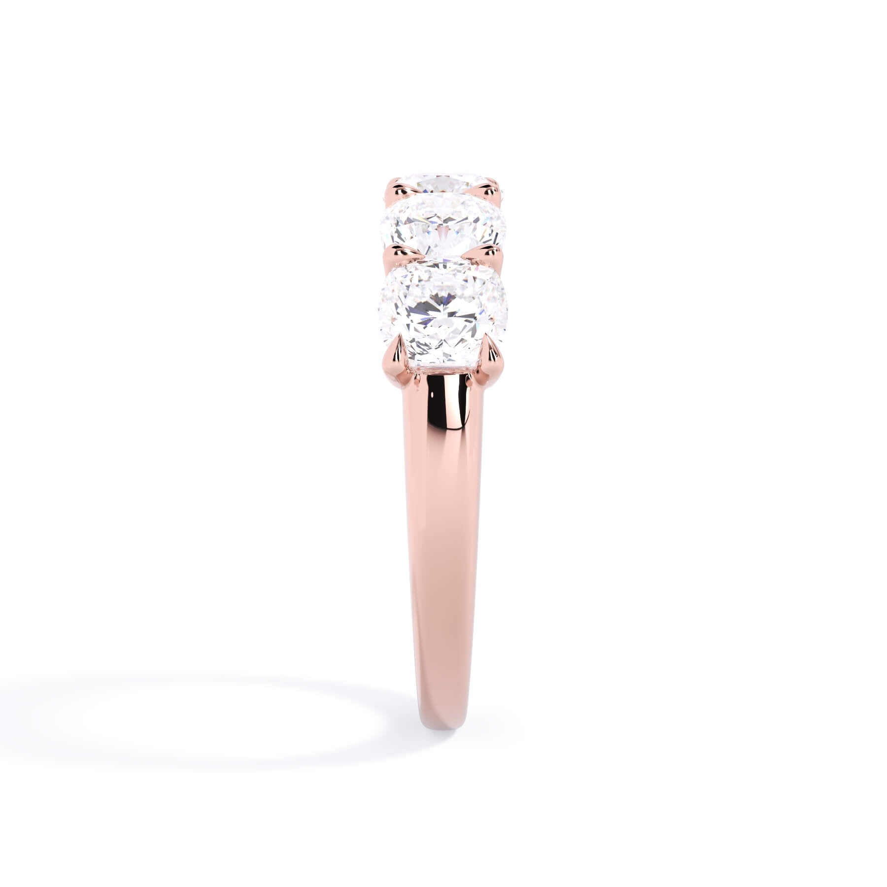 A picture of a five stone diamond wedding ring with cushion shape diamonds that are u prong set in rose gold on a white background with a side profile view.