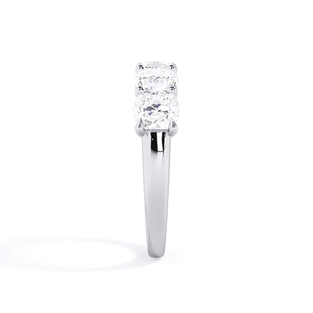 A picture of a five stone diamond wedding ring with cushion shape diamonds that are u prong set in white gold or platinum on a white background with a side profile view.
