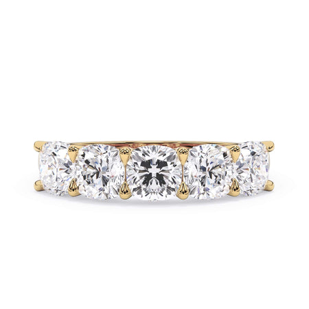 A picture of a five stone diamond wedding ring with cushion shape diamonds that are u prong set in yellow gold on a white background with the ring facing forward, lying down.