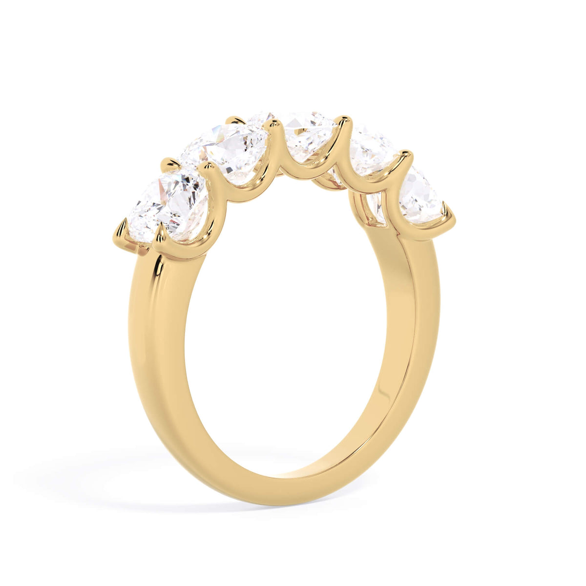A picture of a five stone diamond wedding ring with cushion shape diamonds that are u prong set in yellow gold on a white background with a slightly angled, through the finger view.