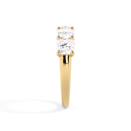 A picture of a five stone diamond wedding ring with cushion shape diamonds that are u prong set in yellow gold on a white background with a side profile view.