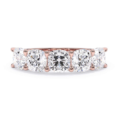 A picture of a five stone diamond wedding ring with cushion shape diamonds that are u prong set in rose gold on a white background with the ring facing forward, lying down.