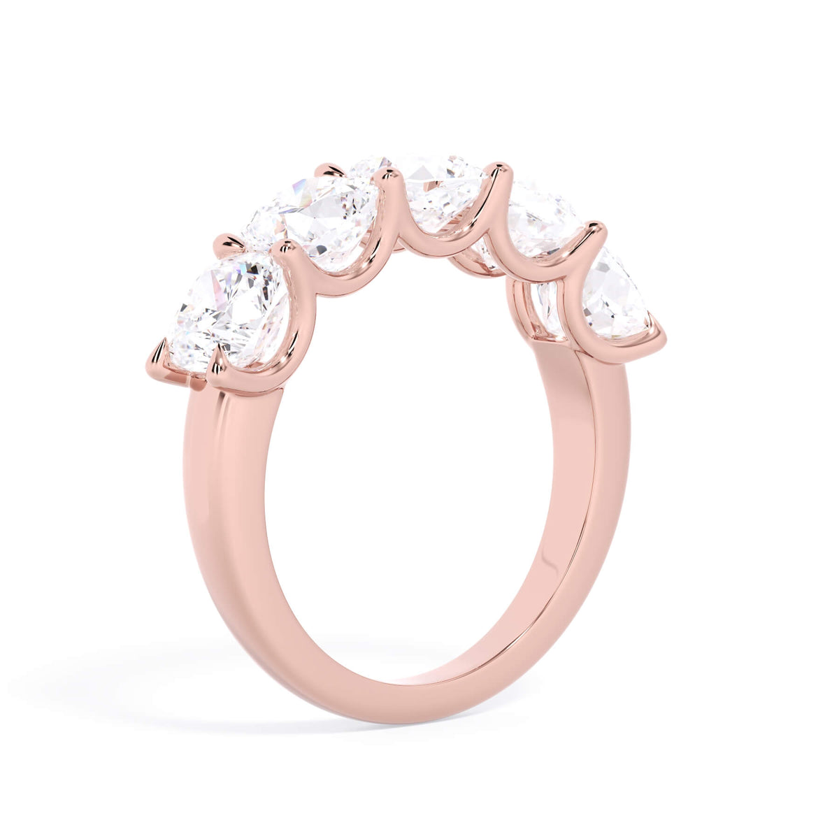 A picture of a five stone diamond wedding ring with cushion shape diamonds that are u prong set in rose gold on a white background with a slightly angled, through the finger view.