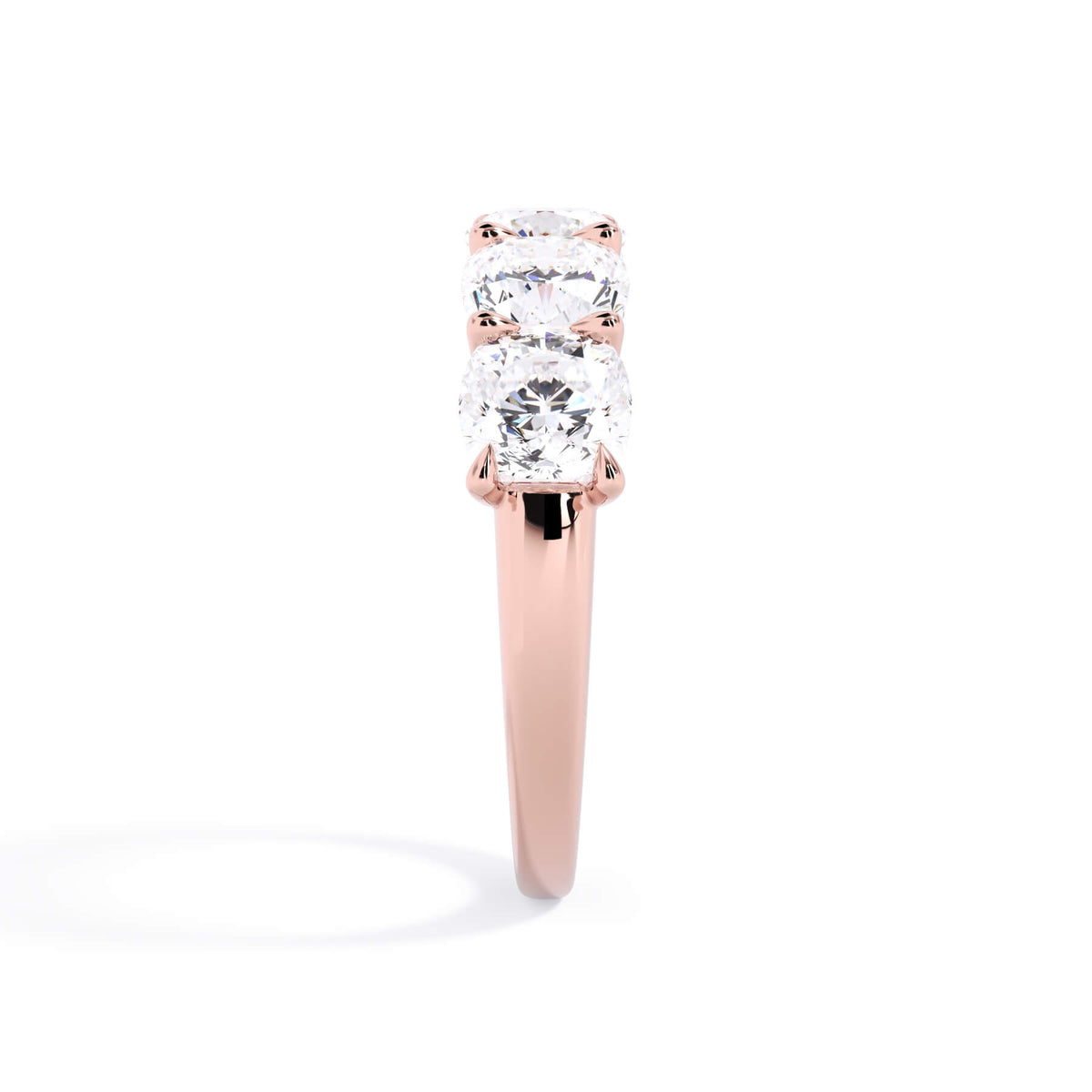 A picture of a five stone diamond wedding ring with cushion shape diamonds that are u prong set in rose gold on a white background with a side profile view.