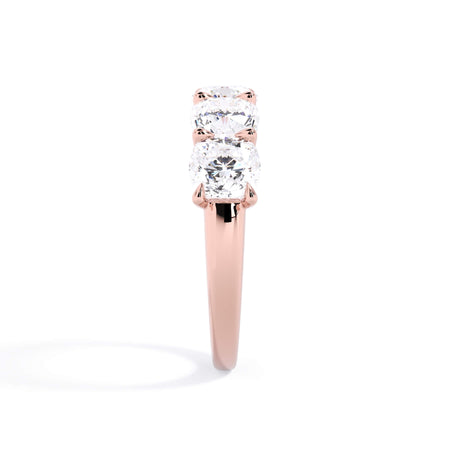 A picture of a five stone diamond wedding ring with cushion shape diamonds that are u prong set in rose gold on a white background with a side profile view.