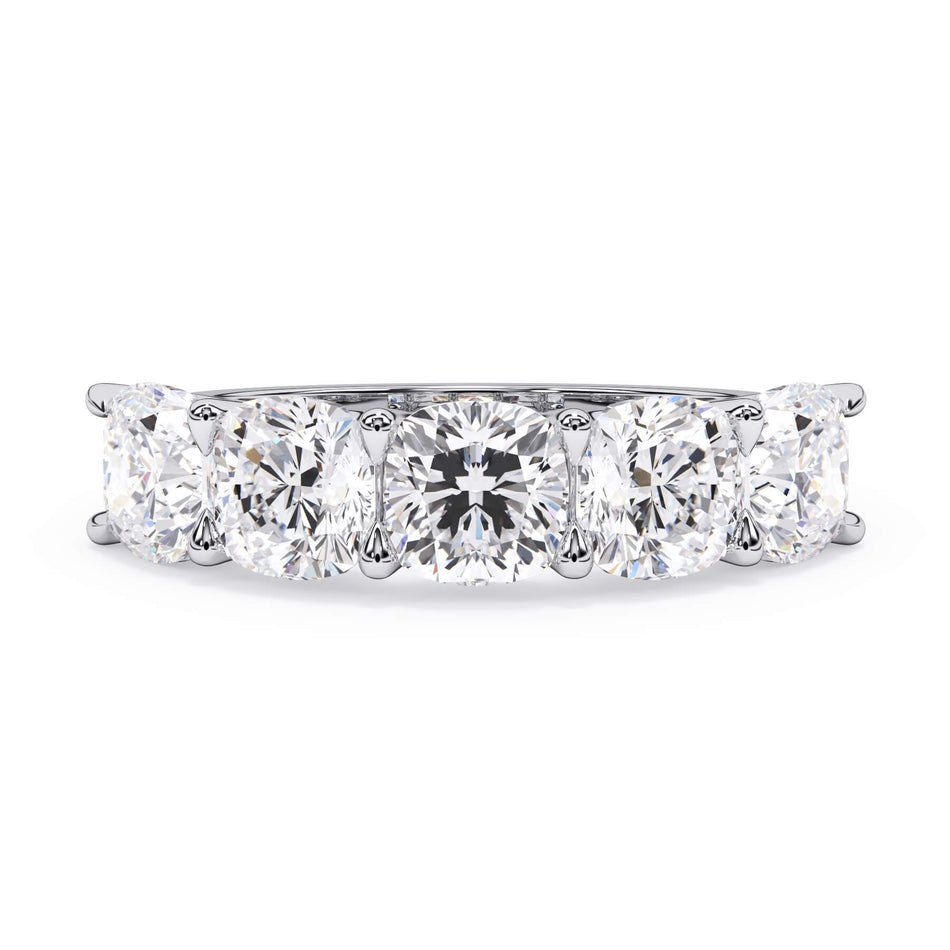 A picture of a five stone diamond wedding ring with cushion shape diamonds that are u prong set in white gold or platinum on a white background with the ring facing forward, lying down.