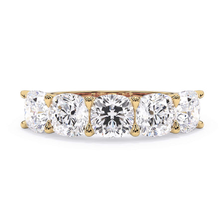 A picture of a five stone diamond wedding ring with cushion shape diamonds that are u prong set in yellow gold on a white background with the ring facing forward, lying down.