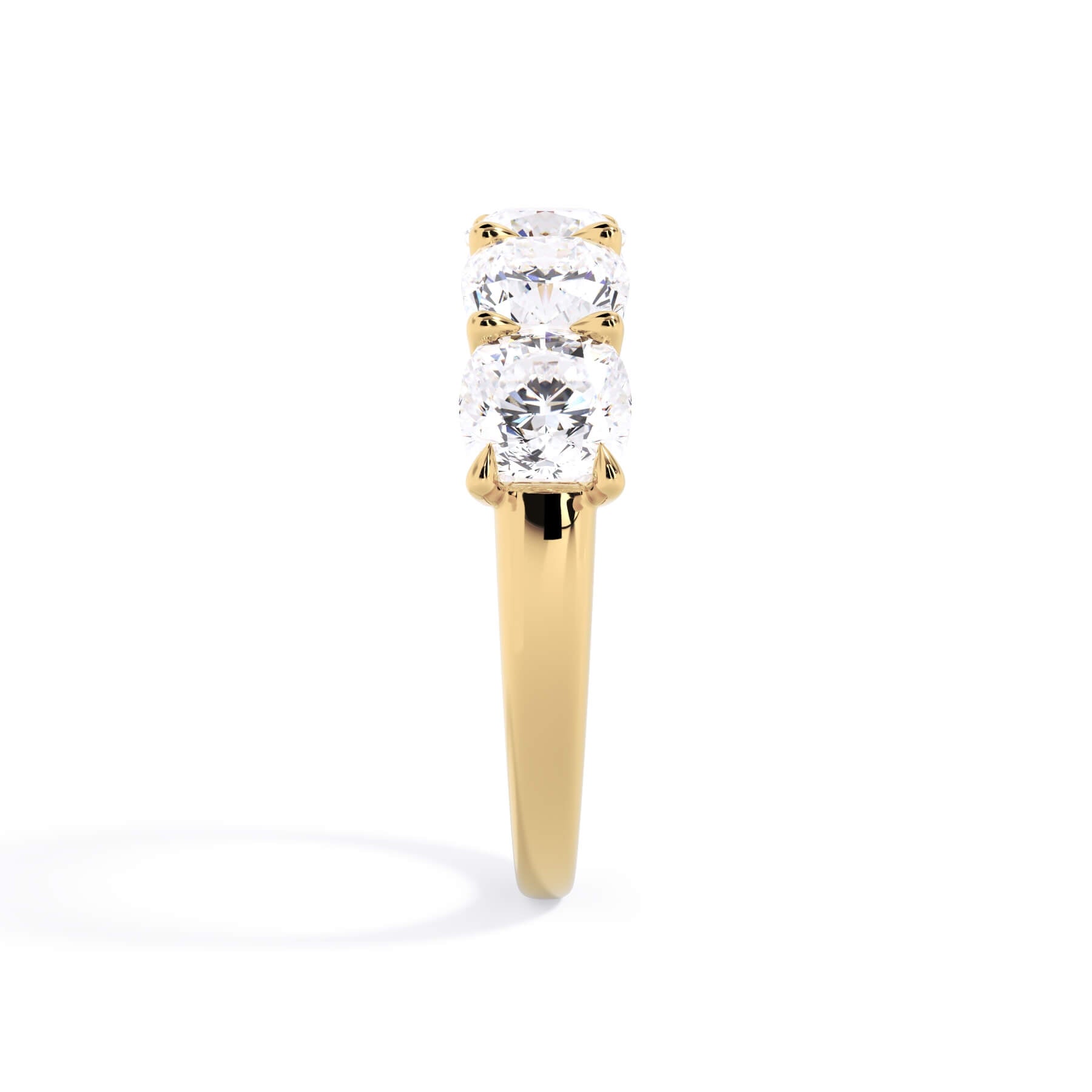 A picture of a five stone diamond wedding ring with cushion shape diamonds that are u prong set in yellow gold on a white background with a side profile view.