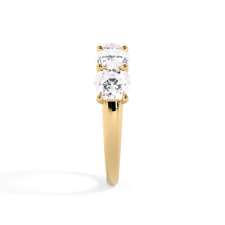 A picture of a five stone diamond wedding ring with cushion shape diamonds that are u prong set in yellow gold on a white background with a side profile view.