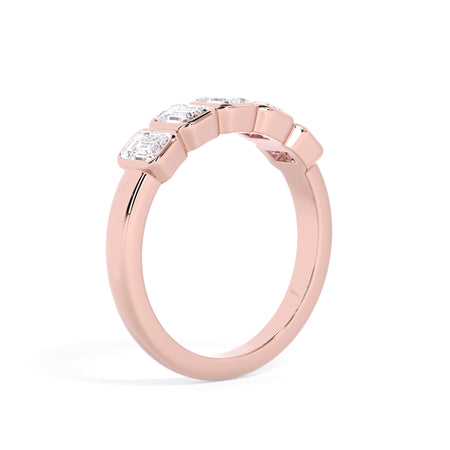 A picture of a five stone diamond wedding ring with emerald cut diamonds that are bezel set in rose gold on a white background with a slightly angled, through the finger view.