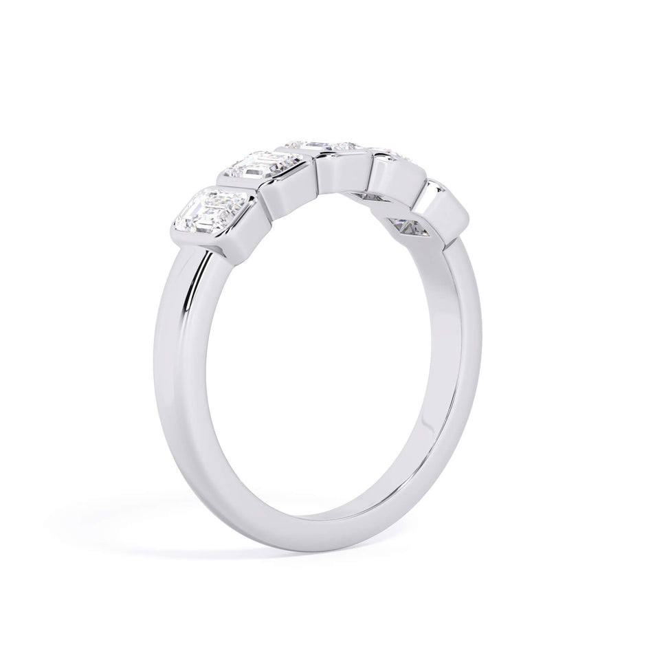 A picture of a five stone diamond wedding ring with emerald cut diamonds that are bezel set in white gold or platinum on a white background with a slightly angled, through the finger view.