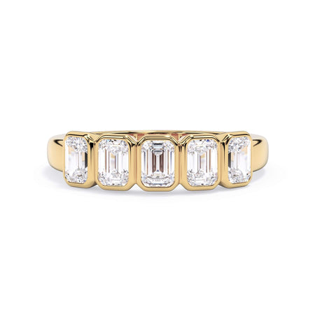 A picture of a five stone diamond wedding ring with emerald cut diamonds that are bezel set in yellow gold on a white background with the ring facing forward, lying down.