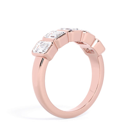 A picture of a five stone diamond wedding ring with emerald cut diamonds that are bezel set in rose gold on a white background with a slightly angled, through the finger view.