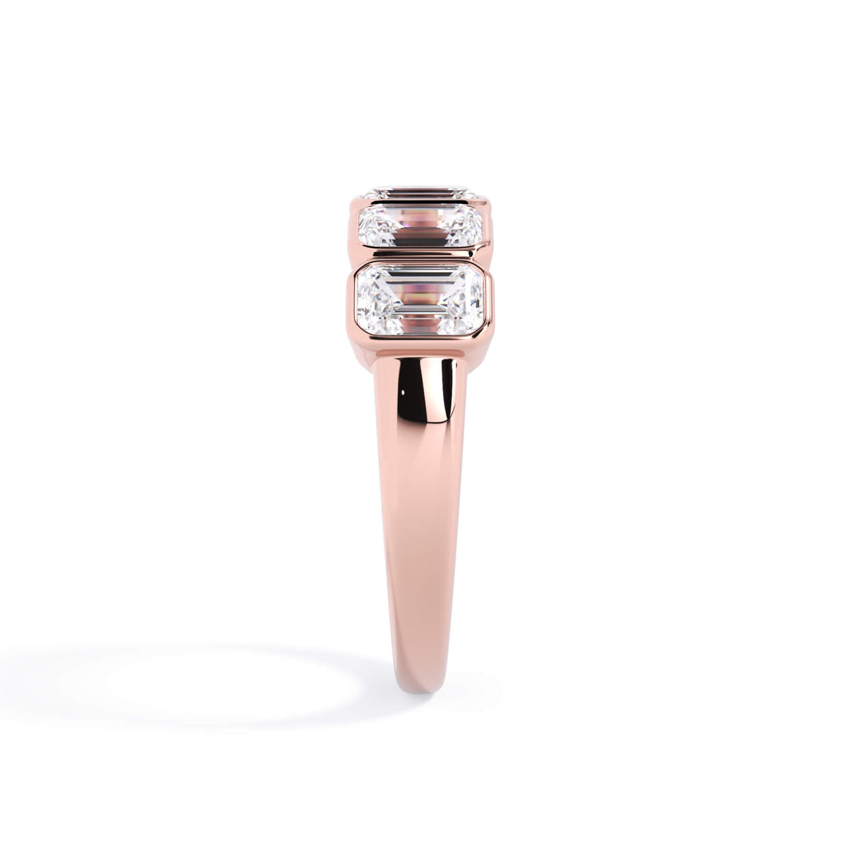 A picture of a five stone diamond wedding ring with emerald cut diamonds that are bezel set in rose gold on a white background with a side profile view.