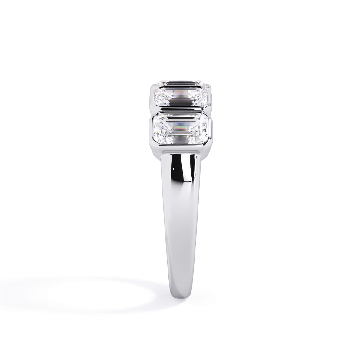 A picture of a five stone diamond wedding ring with emerald cut diamonds that are bezel set in white gold or platinum on a white background with a side profile view.