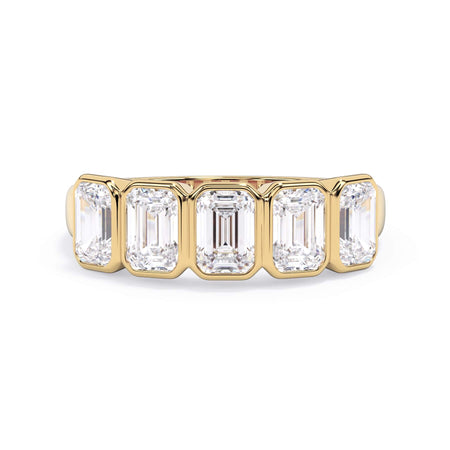 A picture of a five stone diamond wedding ring with emerald cut diamonds that are bezel set in yellow gold on a white background with the ring facing forward, lying down.