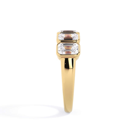 A picture of a five stone diamond wedding ring with emerald cut diamonds that are bezel set in yellow gold on a white background with a side profile view.