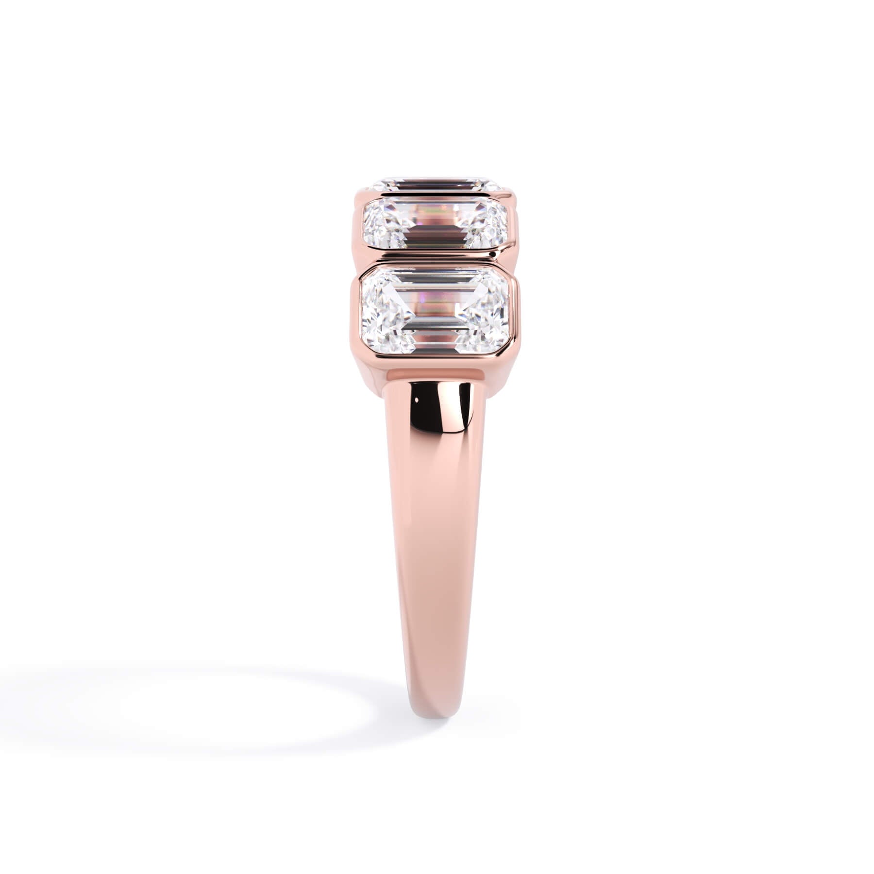 A picture of a five stone diamond wedding ring with emerald cut diamonds that are bezel set in rose gold on a white background with a side profile view.