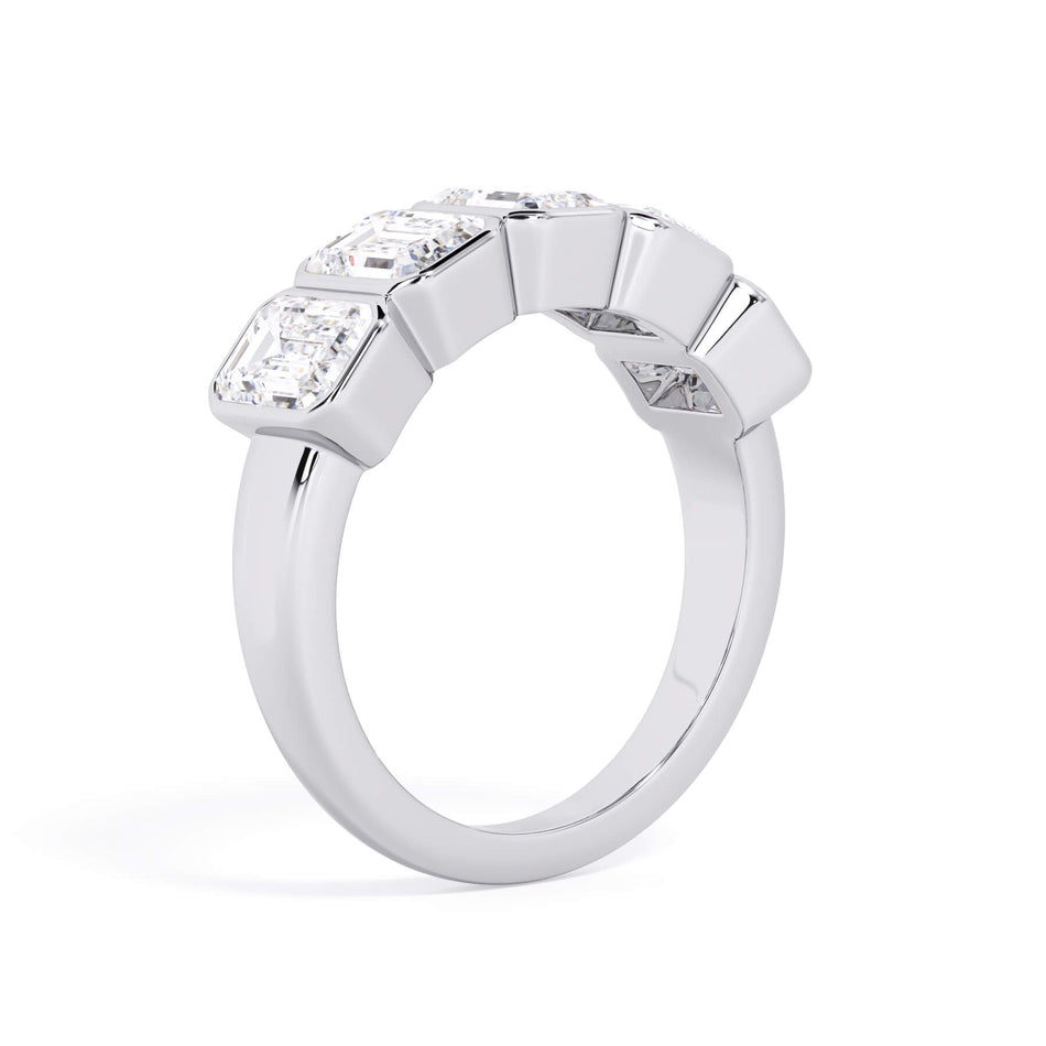 A picture of a five stone diamond wedding ring with emerald cut diamonds that are bezel set in white gold or platinum on a white background with a slightly angled, through the finger view.