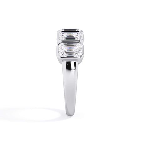 A picture of a five stone diamond wedding ring with emerald cut diamonds that are bezel set in white gold or platinum on a white background with a side profile view.