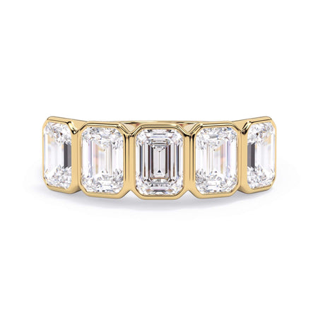A picture of a five stone diamond wedding ring with emerald cut diamonds that are bezel set in yellow gold on a white background with the ring facing forward, lying down.