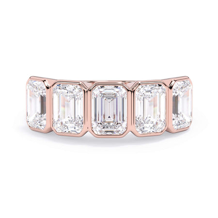 A picture of a five stone diamond wedding ring with emerald cut diamonds that are bezel set in rose gold on a white background with the ring facing forward, lying down.