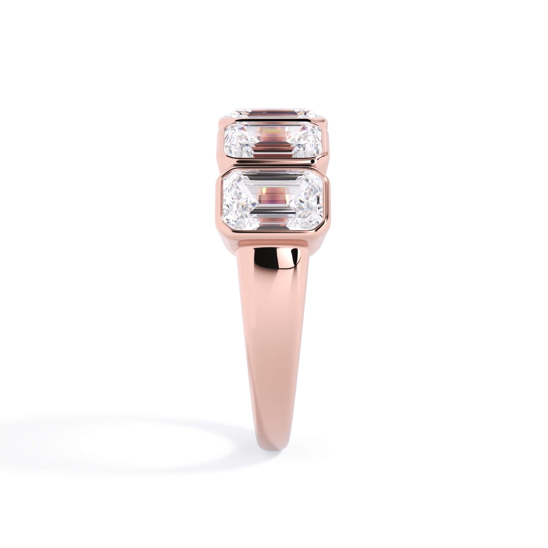 A picture of a five stone diamond wedding ring with emerald cut diamonds that are bezel set in rose gold on a white background with a side profile view.