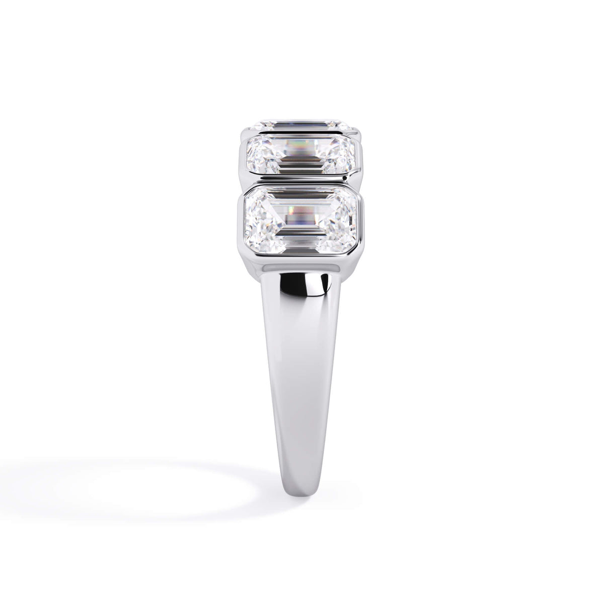 A picture of a five stone diamond wedding ring with emerald cut diamonds that are bezel set in white gold or platinum on a white background with a side profile view.