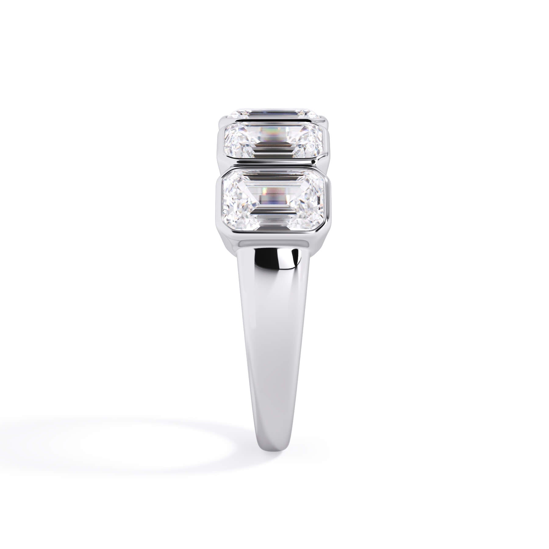 A picture of a five stone diamond wedding ring with emerald cut diamonds that are bezel set in white gold or platinum on a white background with a side profile view.