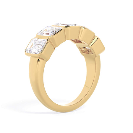 A picture of a five stone diamond wedding ring with emerald cut diamonds that are bezel set in yellow gold on a white background with a slightly angled, through the finger view.