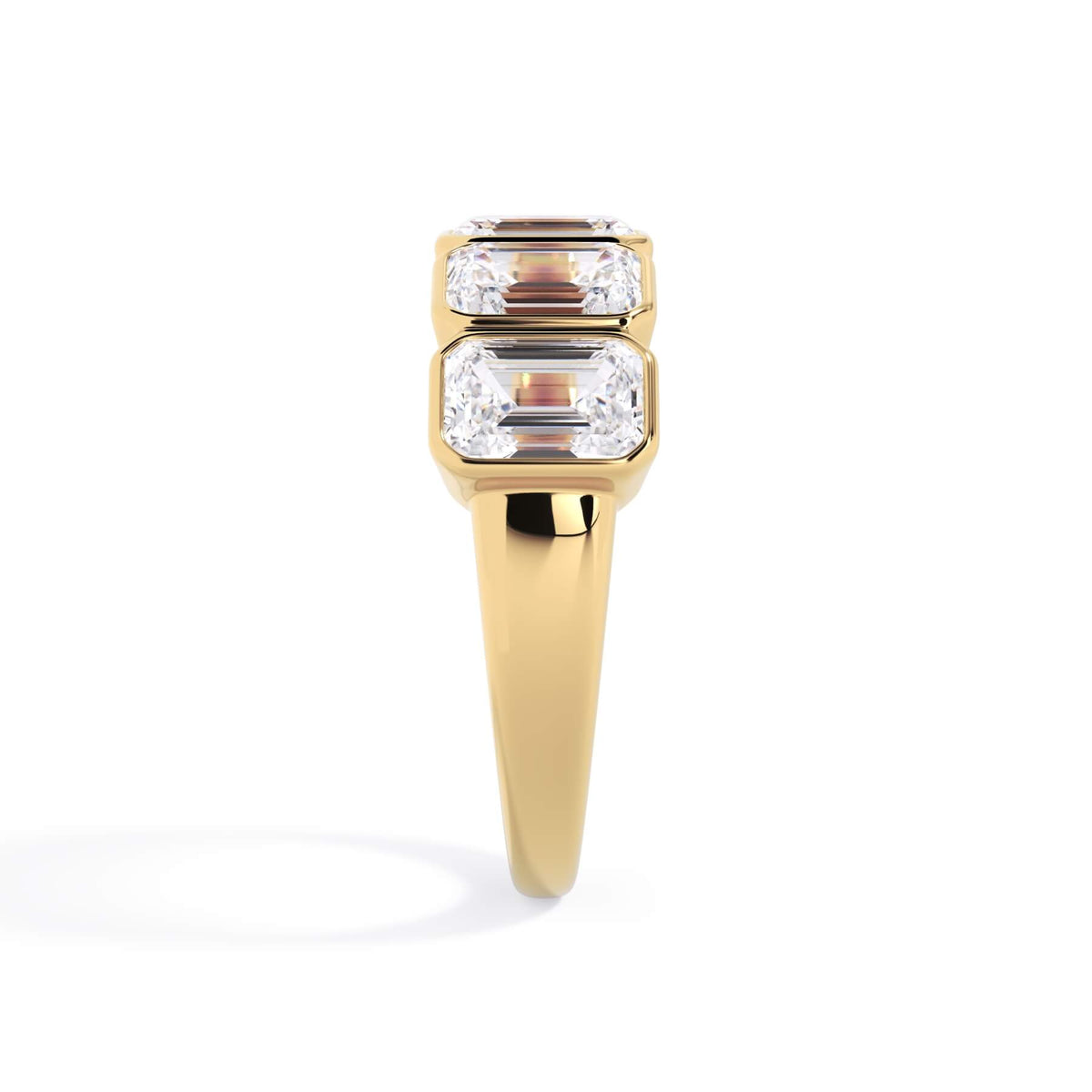 A picture of a five stone diamond wedding ring with emerald cut diamonds that are bezel set in yellow gold on a white background with a side profile view.