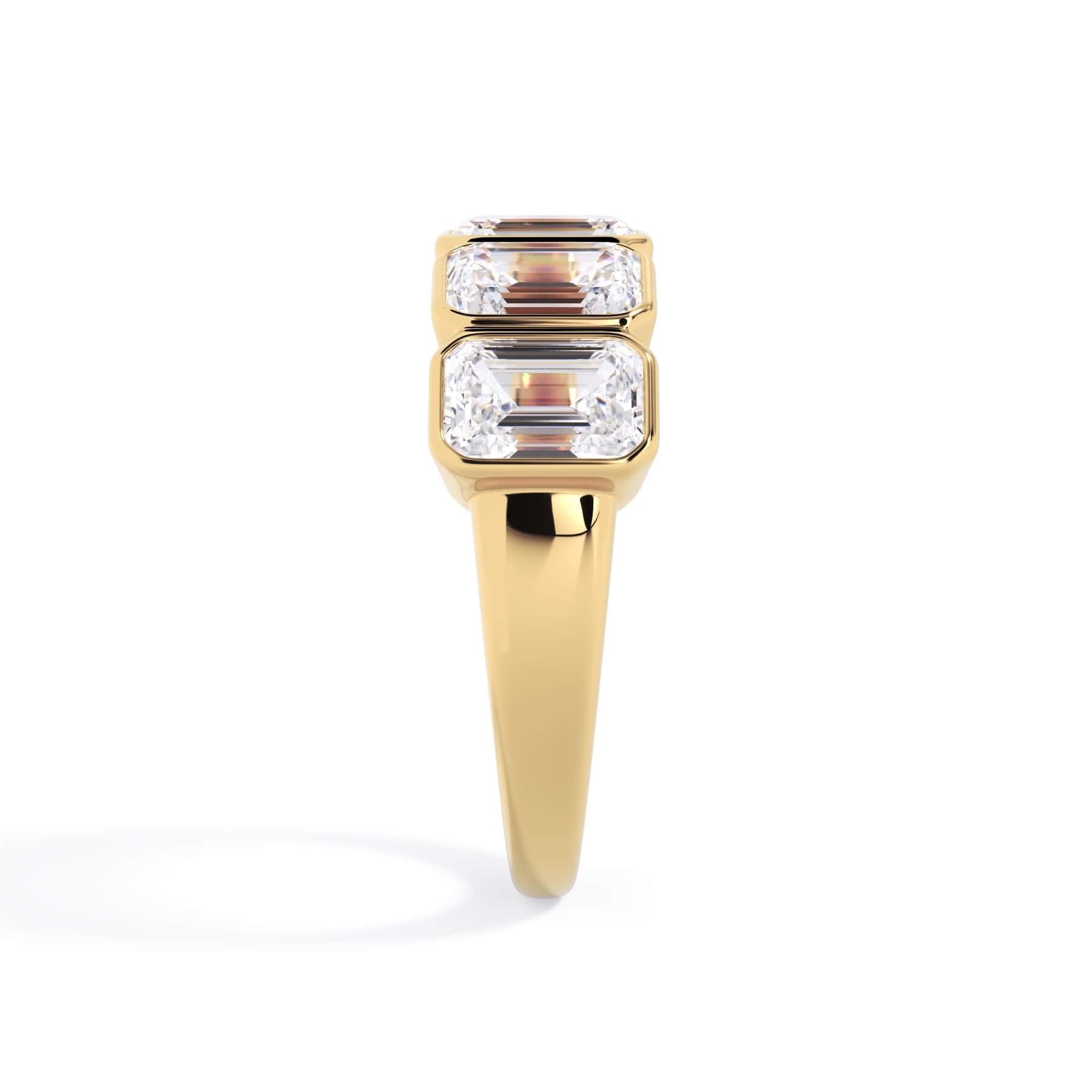 A picture of a five stone diamond wedding ring with emerald cut diamonds that are bezel set in yellow gold on a white background with a side profile view.