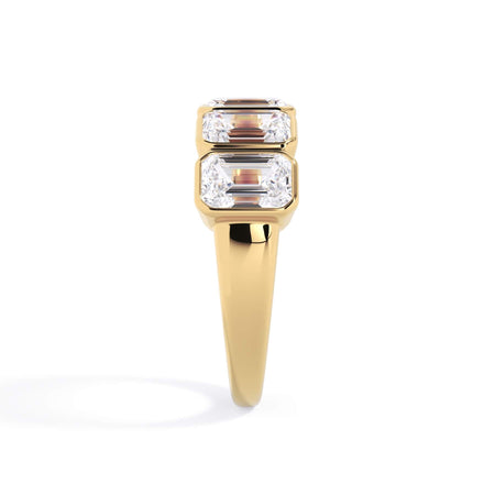 A picture of a five stone diamond wedding ring with emerald cut diamonds that are bezel set in yellow gold on a white background with a side profile view.