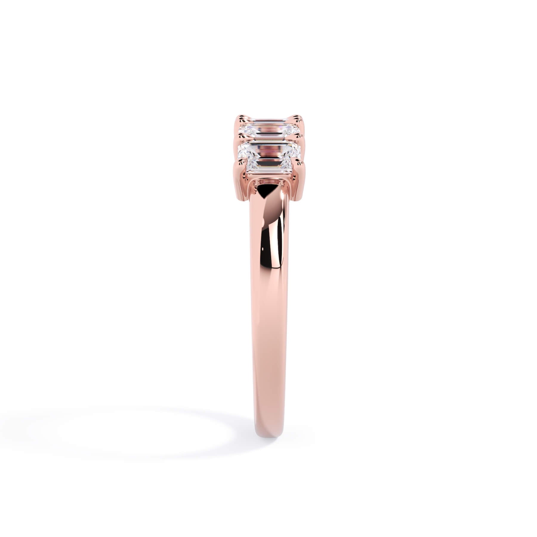 A picture of a five stone diamond wedding ring with emerald cut diamonds that are shared prong set in rose gold on a white background with a side profile view.