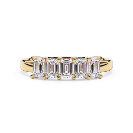 A picture of a five stone diamond wedding ring with emerald cut diamonds that are shared prong set in yellow gold on a white background with the ring facing forward, lying down.
