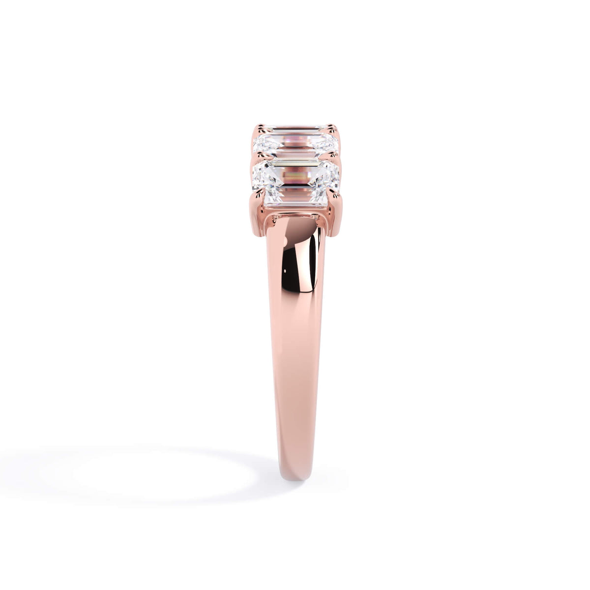 A picture of a five stone diamond wedding ring with emerald cut diamonds that are shared prong set in rose gold on a white background with a side profile view.