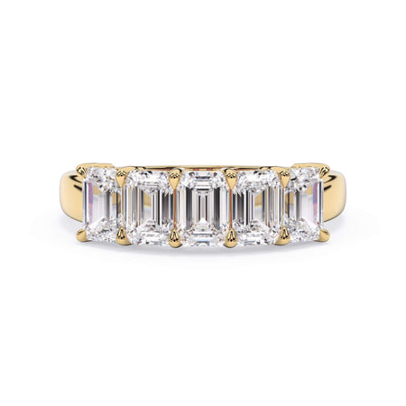 A picture of a five stone diamond wedding ring with emerald cut diamonds that are shared prong set in yellow gold on a white background with the ring facing forward, lying down.
